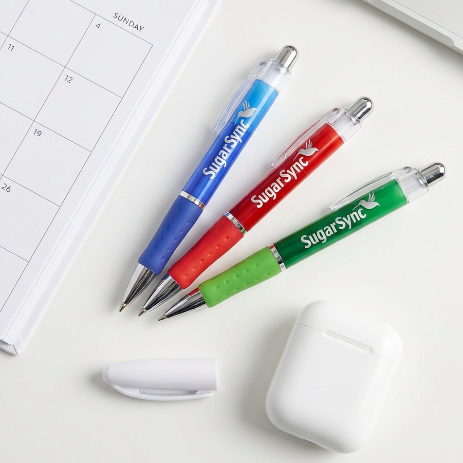 Three SugarSync branded pens in blue, red, and green on a desk with a calendar and mug.